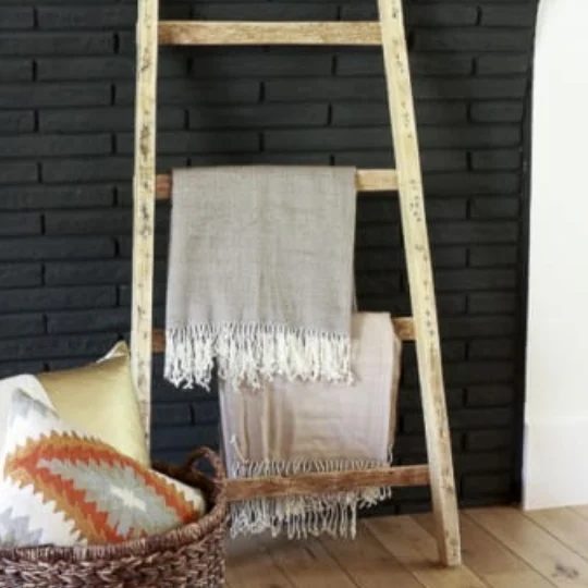 Black Brick Wall With Natural Wood Blanket Ladder Leaning Against It