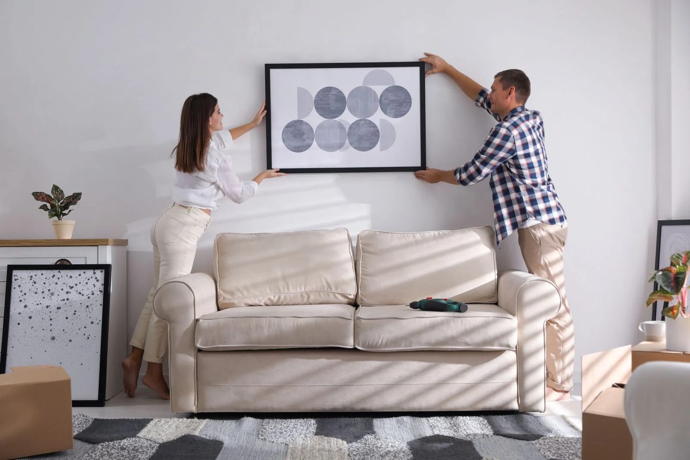 Couple Hanging Art On Wall In Picture Frames