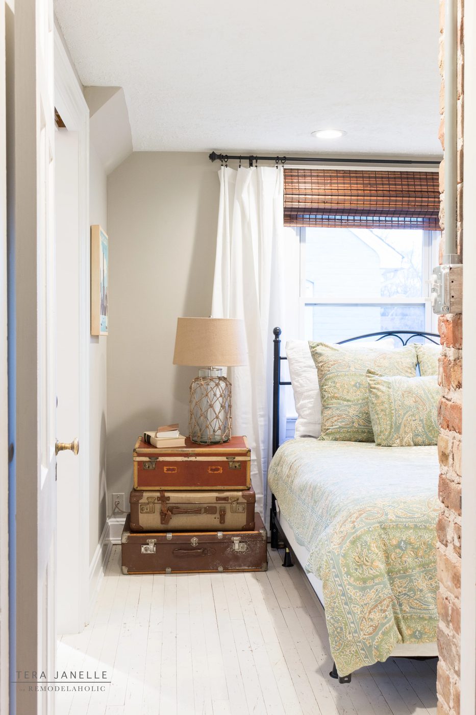 A striking travel-inspired master bedroom with an exposed brick wall and a striking built-in bookshelf and storage nook. Tera Janelle on Bekob.com