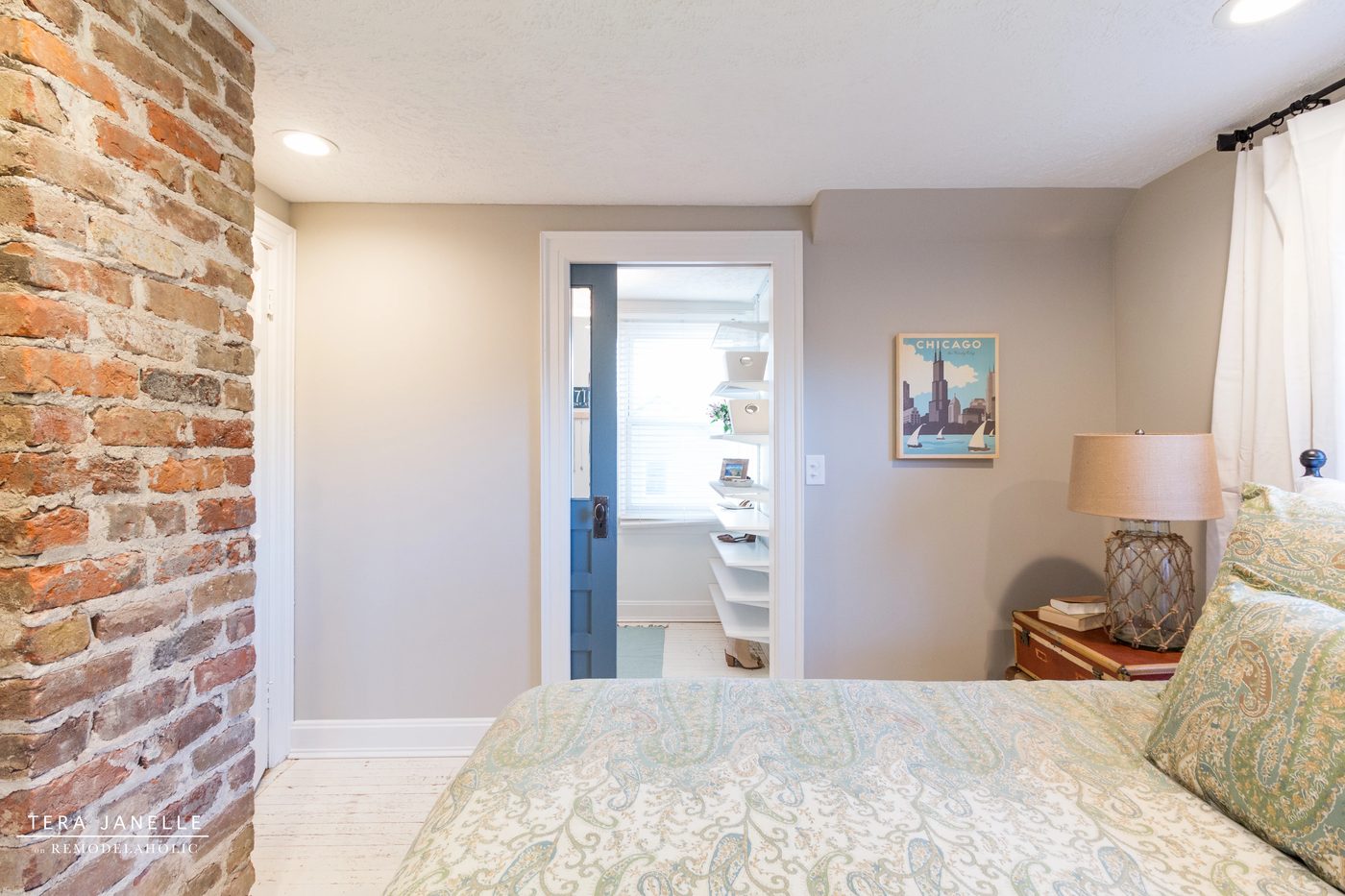 A striking travel-inspired master bedroom with an exposed brick wall and a striking built-in bookshelf and storage nook. Tera Janelle on Bekob.com