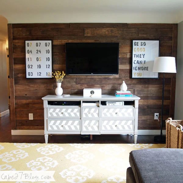 symmetrical canvases around the television, on a stained wood plank wall (Cape 27 Blog)