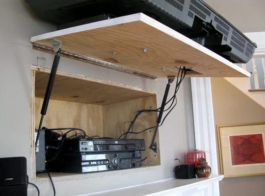 hinged TV compartment to hide electronics and cords behind television (via Apartment Therapy)