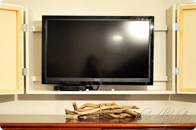 build a frame and box to hide the television behind hinged art canvas doors (dixiedelights)