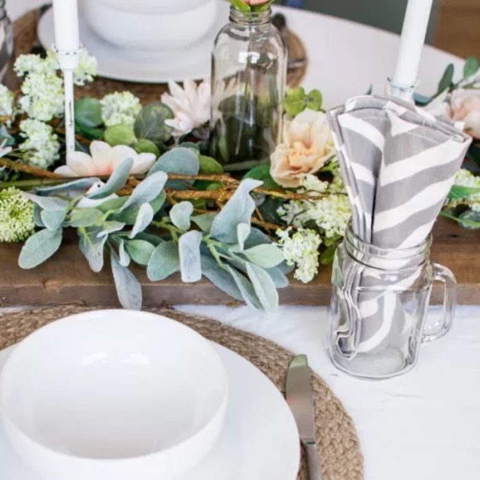 Tablescape Image With White Dishes, Glass Mason Jar Cup, Striped Napkins, And Floral Bouquet