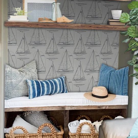 Nautical Room With Uholstered Sitting Bench, Wicker Baskets Underneat, Blue And Grey Pillows With Sail Boat Wallpaper