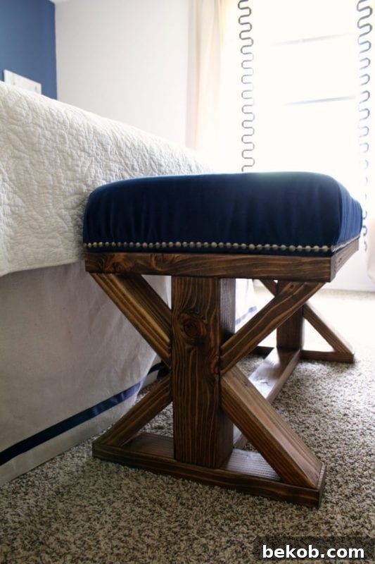 Farmhouse style X-bench built with 2x4s, featuring an upholstered top for added comfort. Ideal for entryways or bedrooms.