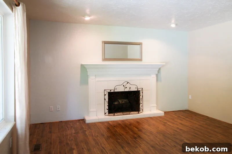 Original simple fireplace mantel with white tile and white painted mantel before DIY makeover