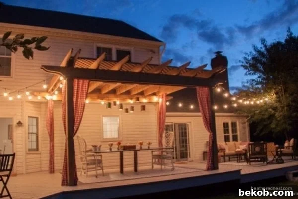 Pergola with hanging string lights, curtains, and dinner table at night