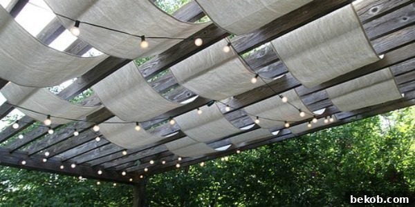 Drop cloth sail pergola with outdoor string lights