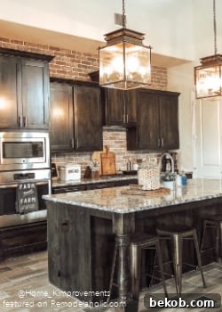 Modern farmhouse kitchen with black cabinets and a stunning full-wall brick backsplash by Home Kimprovements, adding rustic charm.