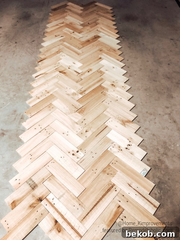 Pallet wood pieces laid out on the floor, ready for installation in a herringbone pattern to create an accent ceiling in a farmhouse entryway.