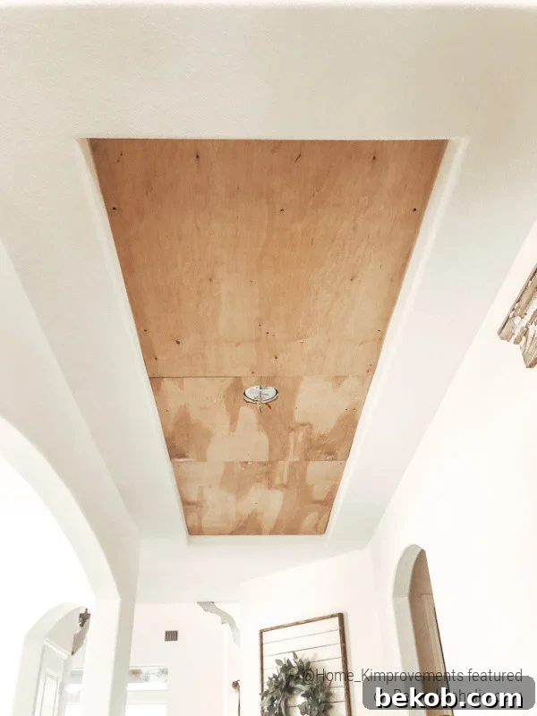 Plywood backing installed within a tray ceiling inset, providing a solid base for a rustic wood pattern, part of a farmhouse entryway renovation.