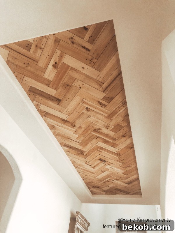 Detailed view of cut edge pieces in a DIY chevron herringbone wood ceiling inset, ready for framing in a farmhouse entryway.