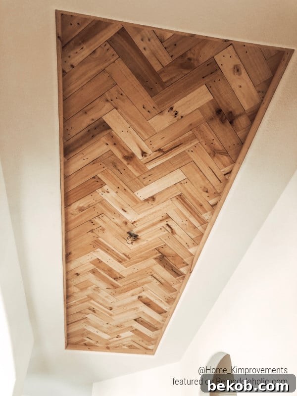 Installing a DIY wood frame around a herringbone pallet wood ceiling accent in a farmhouse entryway, adding a refined finish.