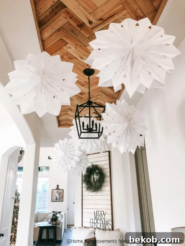 White paper bag snowflakes suspended from a new pallet wood herringbone ceiling in a modern farmhouse entryway, decorated for winter.