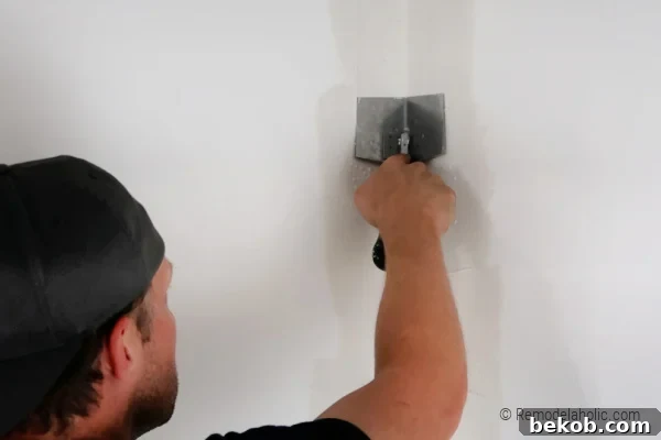 Using Corner Tool To Skim Coat Walls For Smooth Texture, Remodelaholic