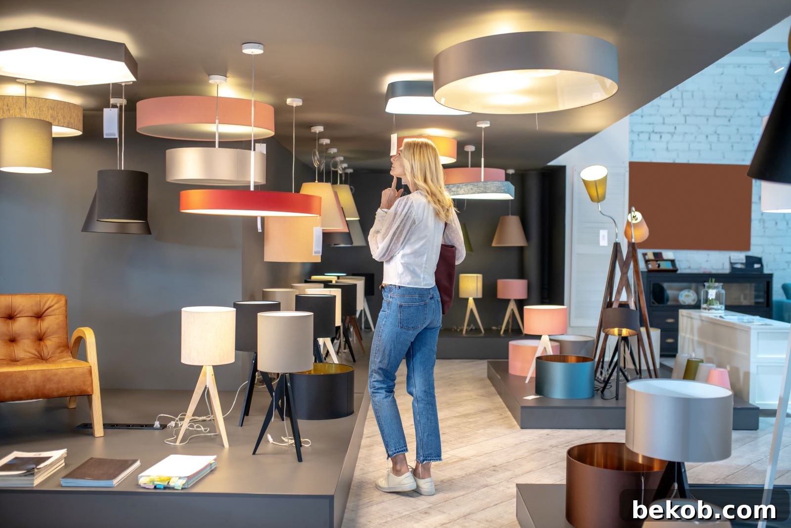 Woman carefully choosing a modern lamp in a showroom, emphasizing the critical decision-making process for materials in minimalist design.