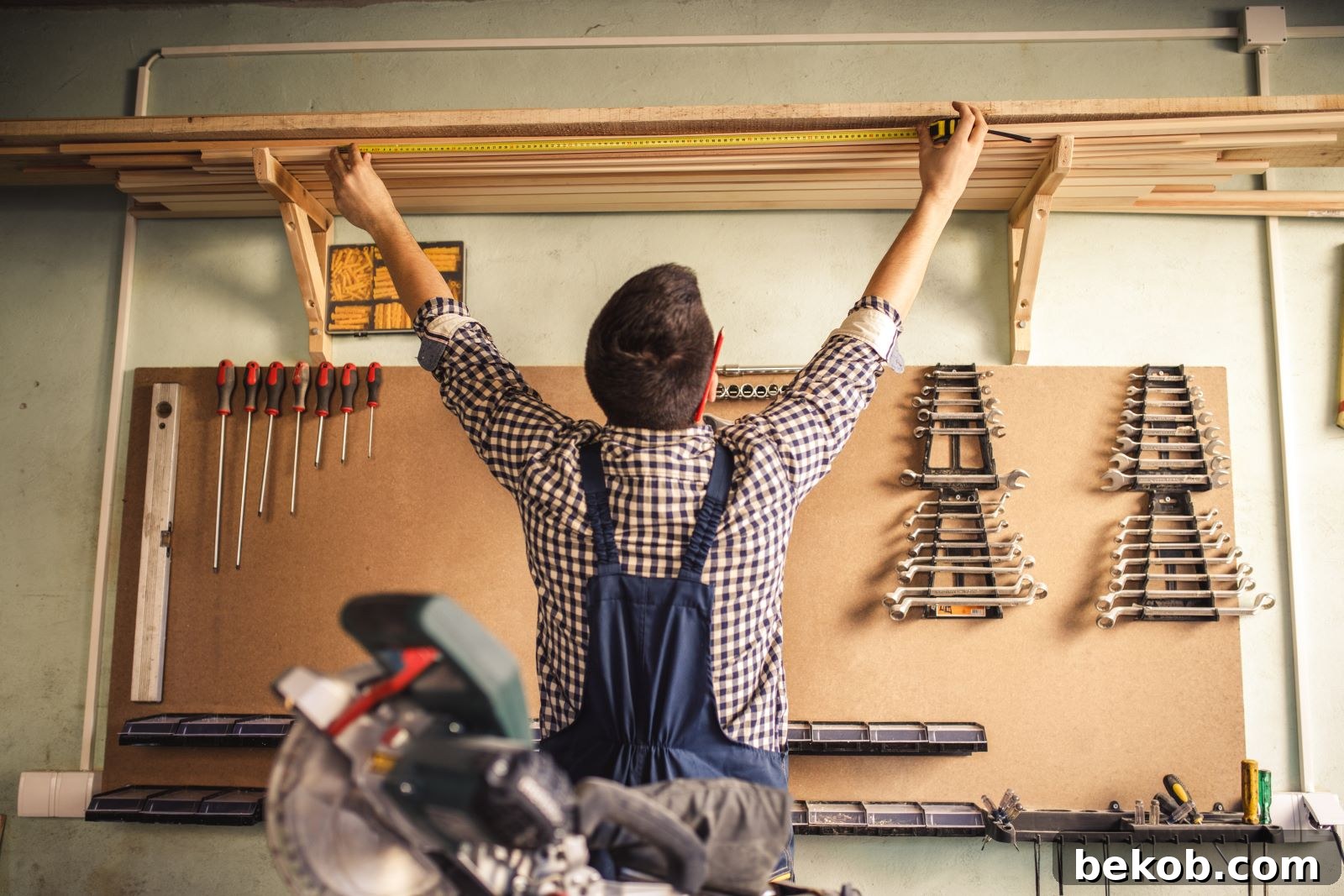 Man standing in a clean, organized finished garage with tools and storage, planning a garage layout for transformation.