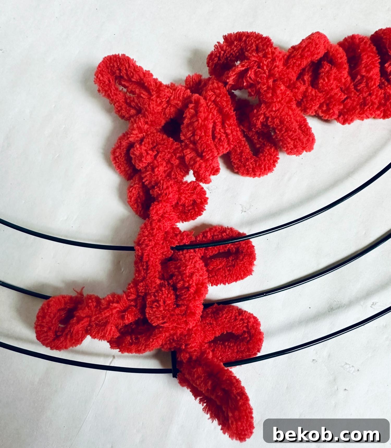 Tying the red loop yarn onto the wire wreath form