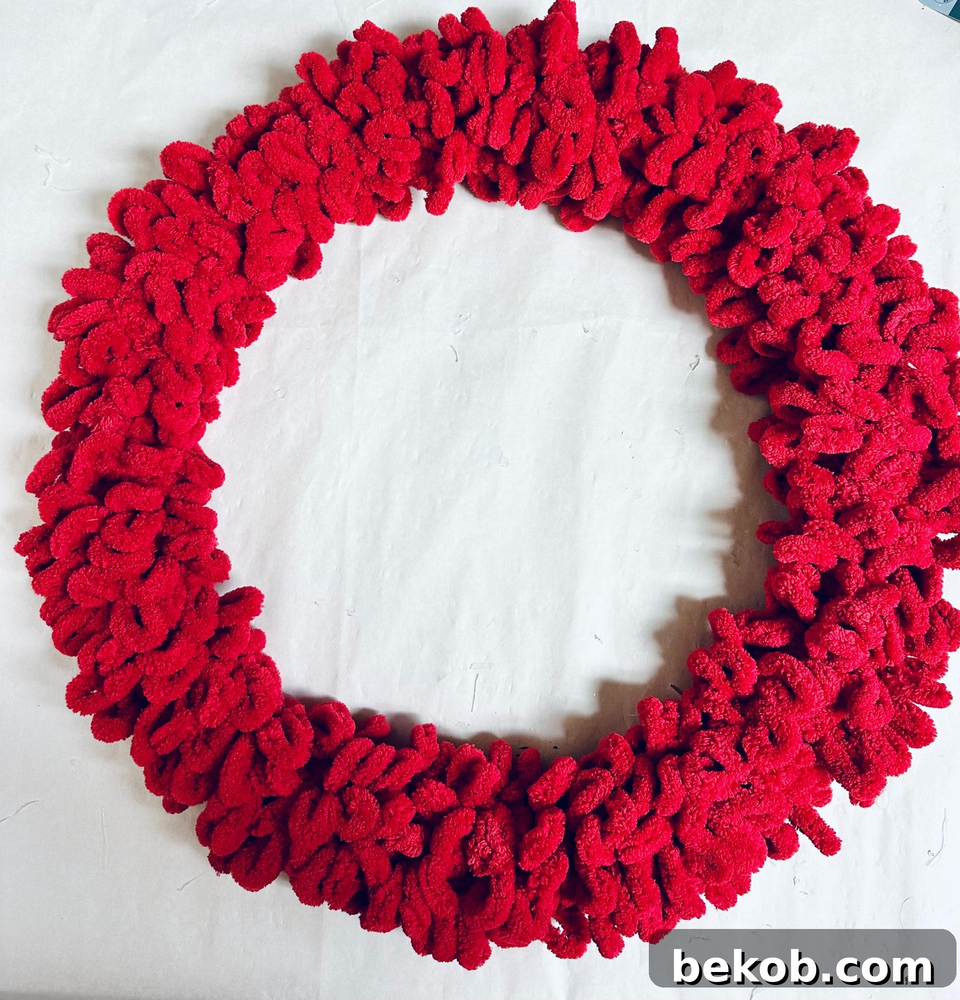 Applying hot glue to secure the loop yarn on the wreath