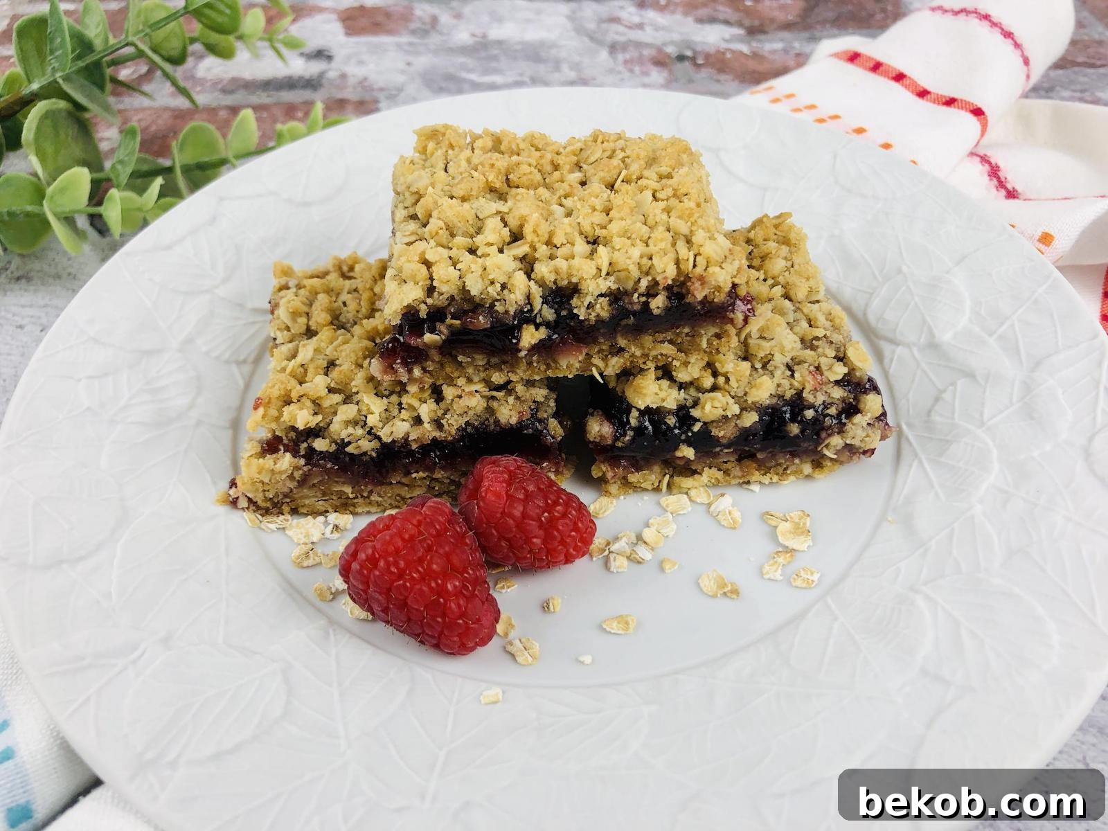 Freshly baked Raspberry Oatmeal Bars, showcasing a golden oat crumble topping and vibrant raspberry filling.