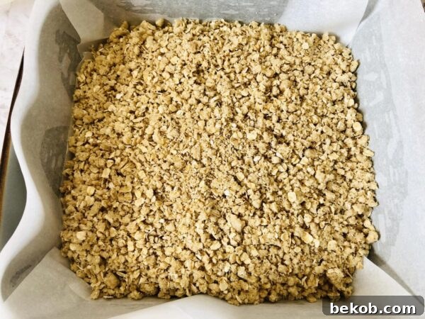 Pressing the oat crust into the baking pan.