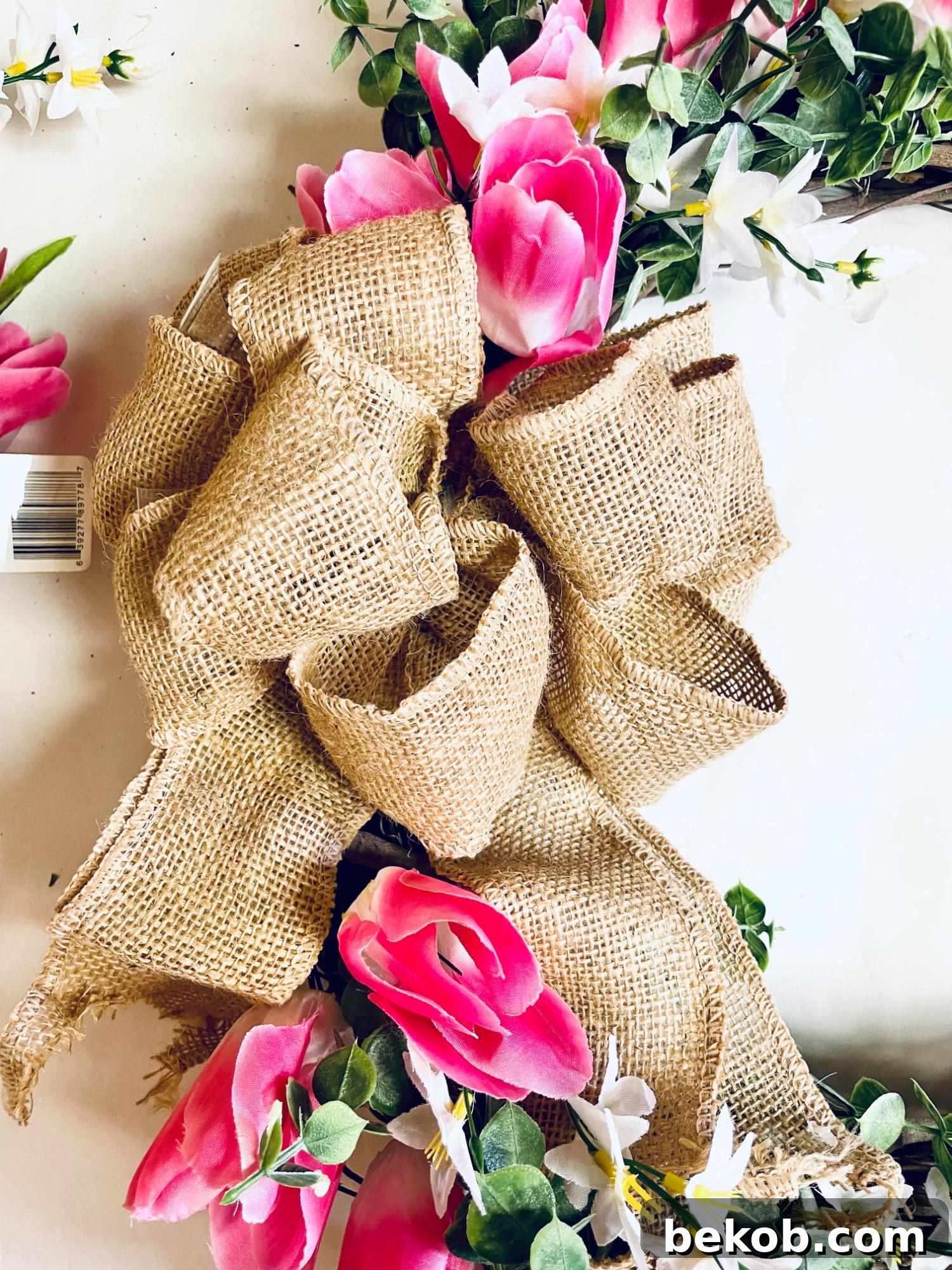Securing a burlap bow to a DIY spring floral wreath