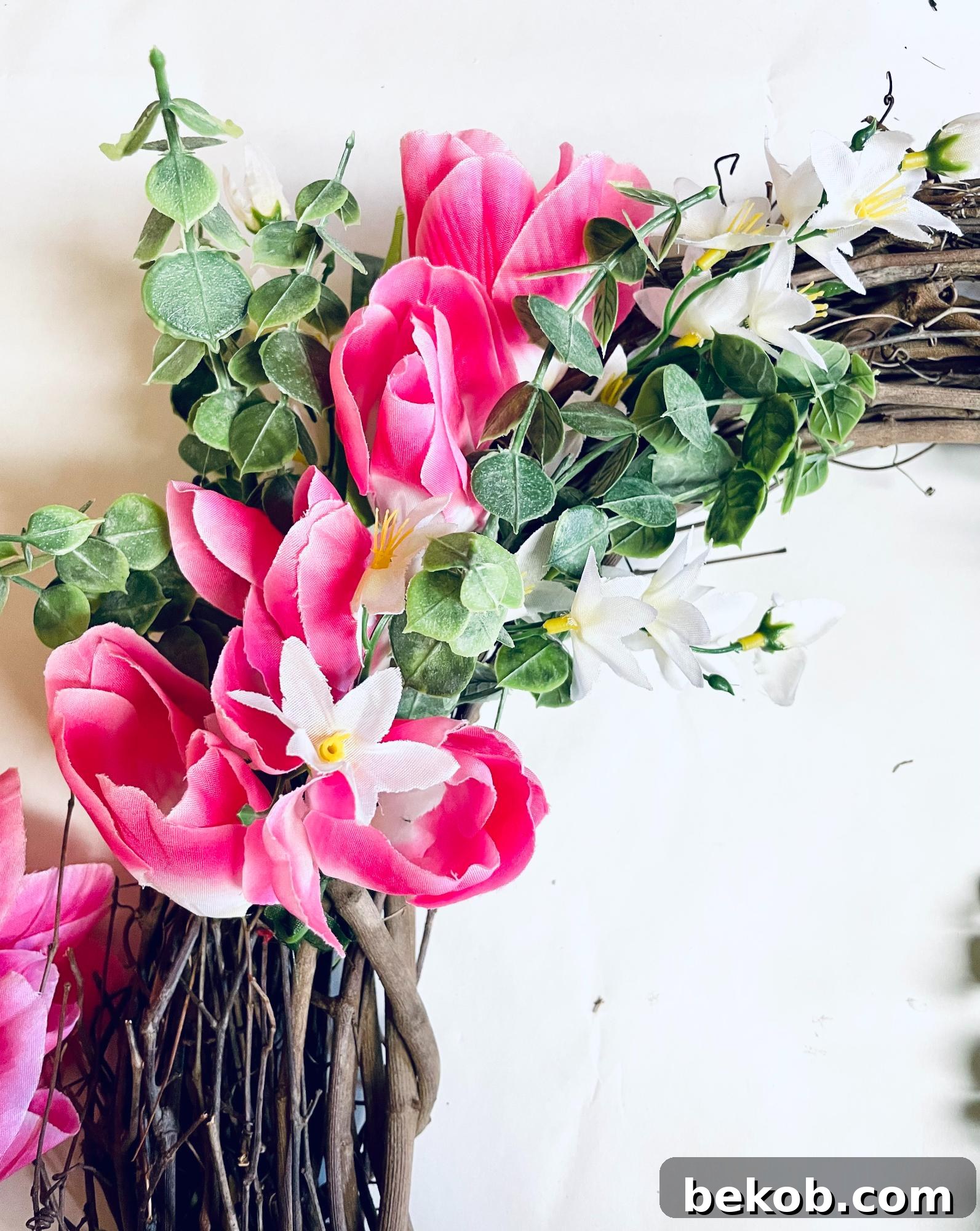 Adding tulips, greenery, and small white flowers to the grapevine wreath