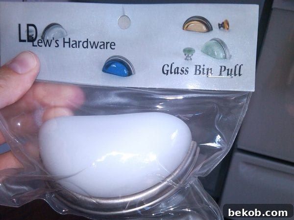Close-up of unique milk glass drawer pulls on gray painted kitchen cabinets