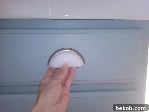 Detailed view of white milk glass drawer pulls on newly painted gray kitchen cabinets