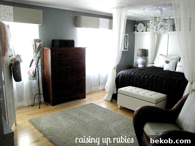 Master bedroom after renovation, showcasing black and white decor with a bed and chandelier