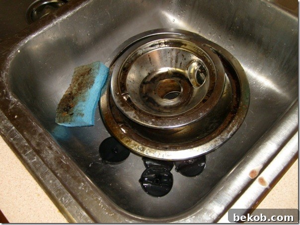 Close-up of the original kitchen range top, showing heavy grime and ineffective use of protective foil.