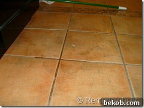 Close-up of the grimy, fake Saltillo-style kitchen floor tile before cleaning or renovation.