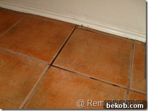 Another view of the dirty and worn kitchen floor tile, illustrating the need for deep cleaning and potential replacement.