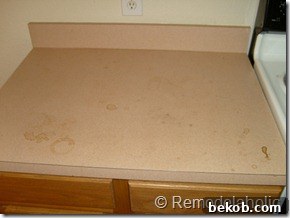 Another view of the stained peachy-pink kitchen countertops, emphasizing the extent of the discoloration.