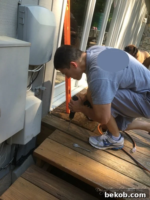 DIY Utility Box Cover - Wood Screen for the Side of the House Eyesores. This image displays the use of a paddle bit to create a larger hole in the stairs, part of accommodating the screen supports.