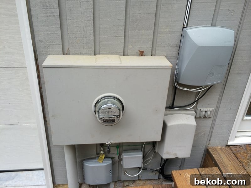 Before DIY utility box cover - utility boxes on the side of the house, showing a close-up of the clutter of meters and wires that detract from curb appeal.