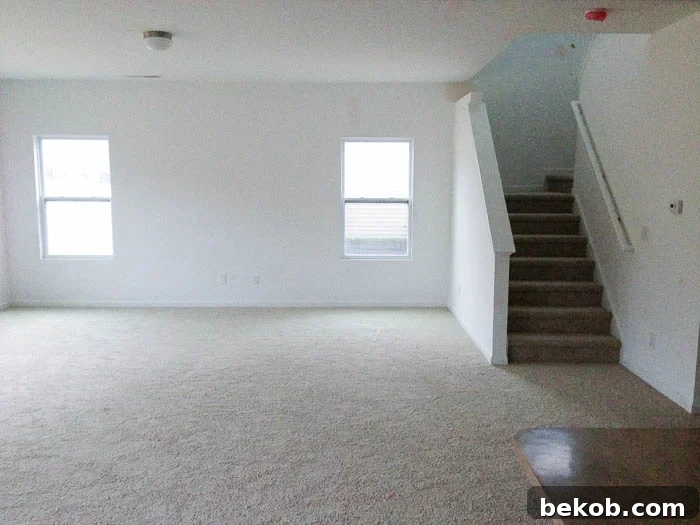 Before: A plain living room before Craftsman window trim and a fireplace
