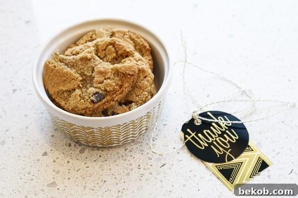 A hand holding a cookie from a ramekin, decorated with a printable gift tag