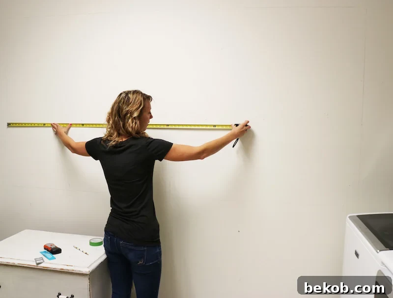 Carefully measuring the wall to determine the precise placement for the new pegboard storage system.