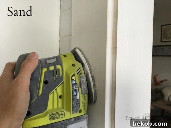 Sanding the newly installed trim to ensure a smooth surface for painting.