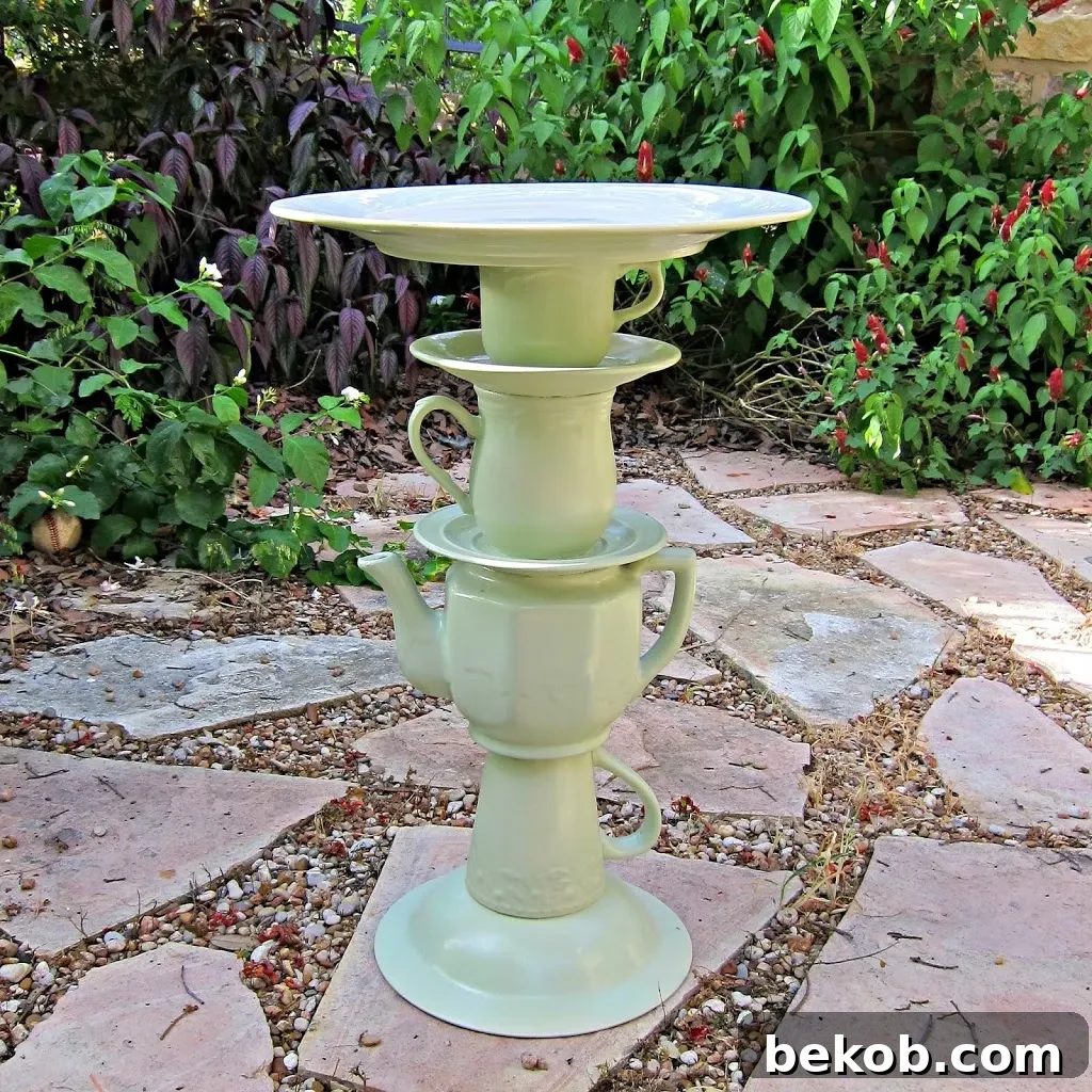 Charming bird bath created by stacking old teacups, saucers, and a teapot, all unified with spray paint.