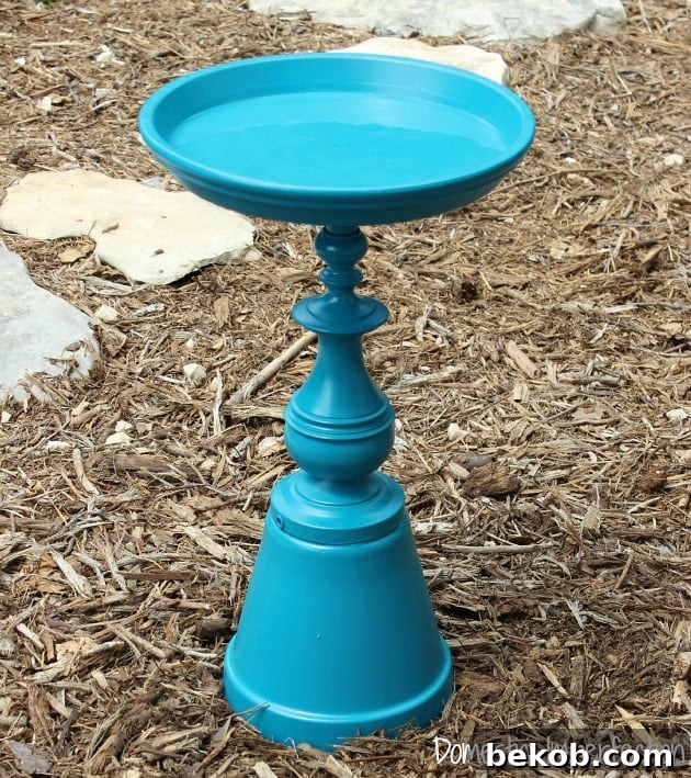Upcycled table leg or lamp base transformed into a beautiful bird bath with a terra cotta saucer.
